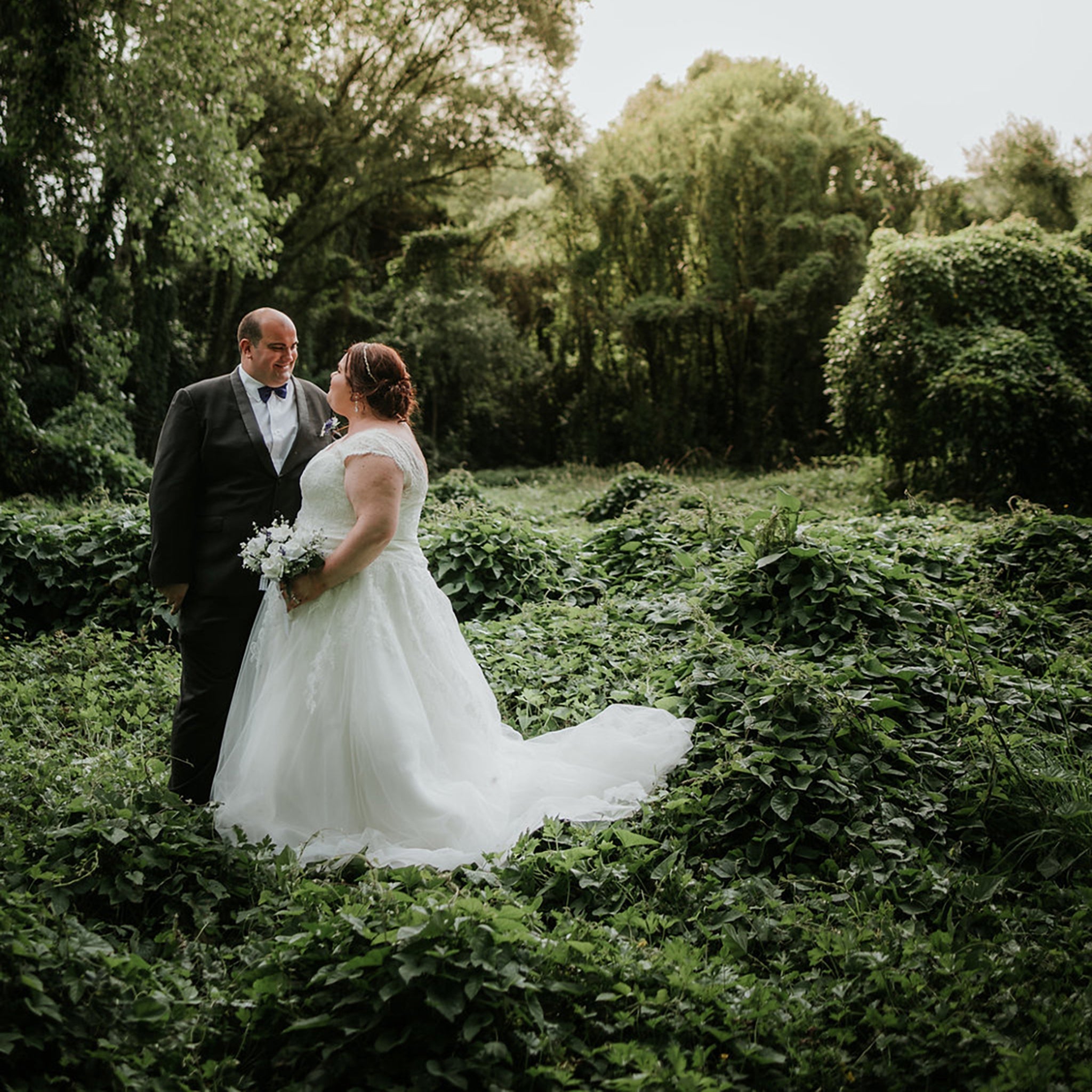 Bride and Groom standing infront of a stunning green forest backdrop at their Waitakere Wedding