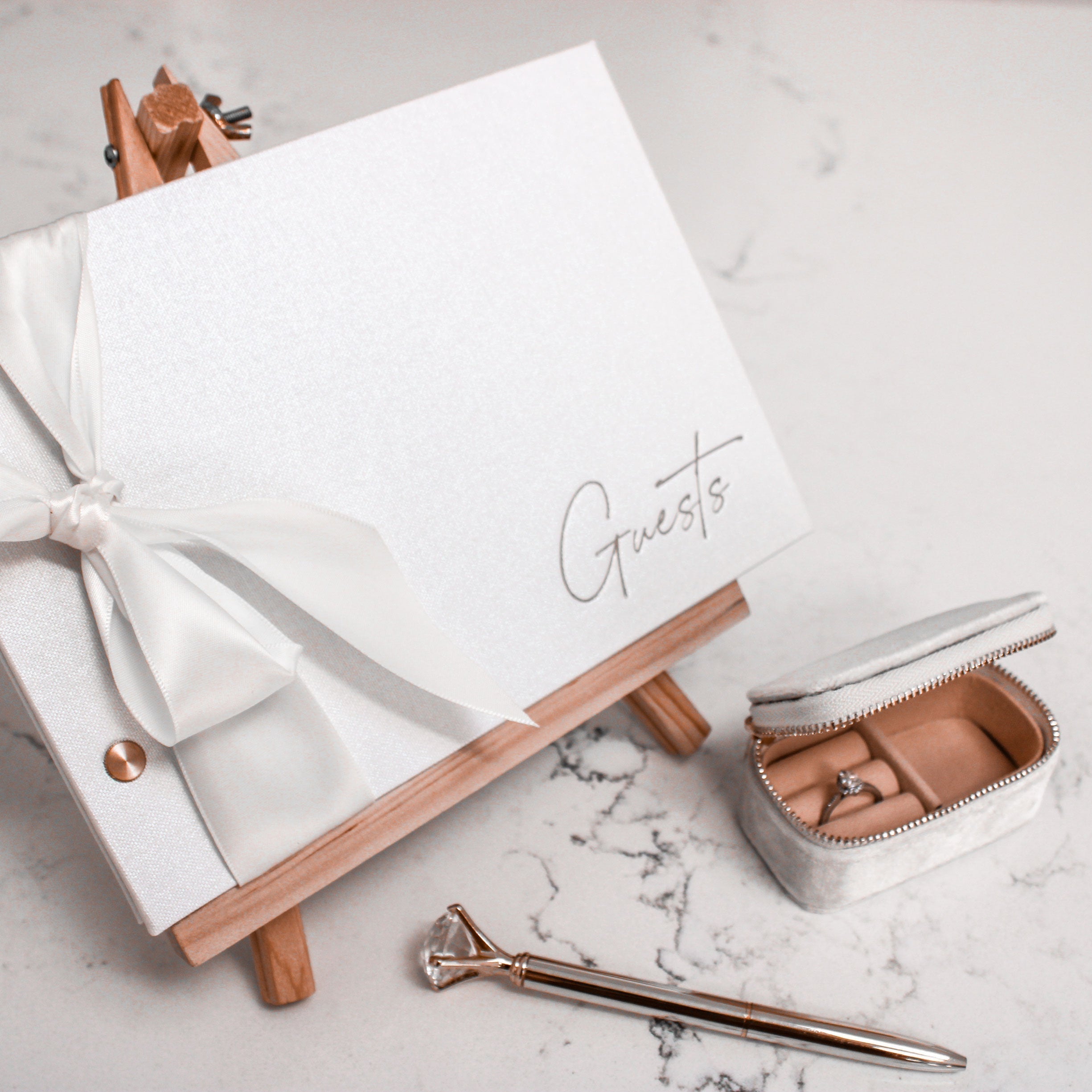 white-wedding-guest-book-on-marble-table-with-pen-and-ring-box