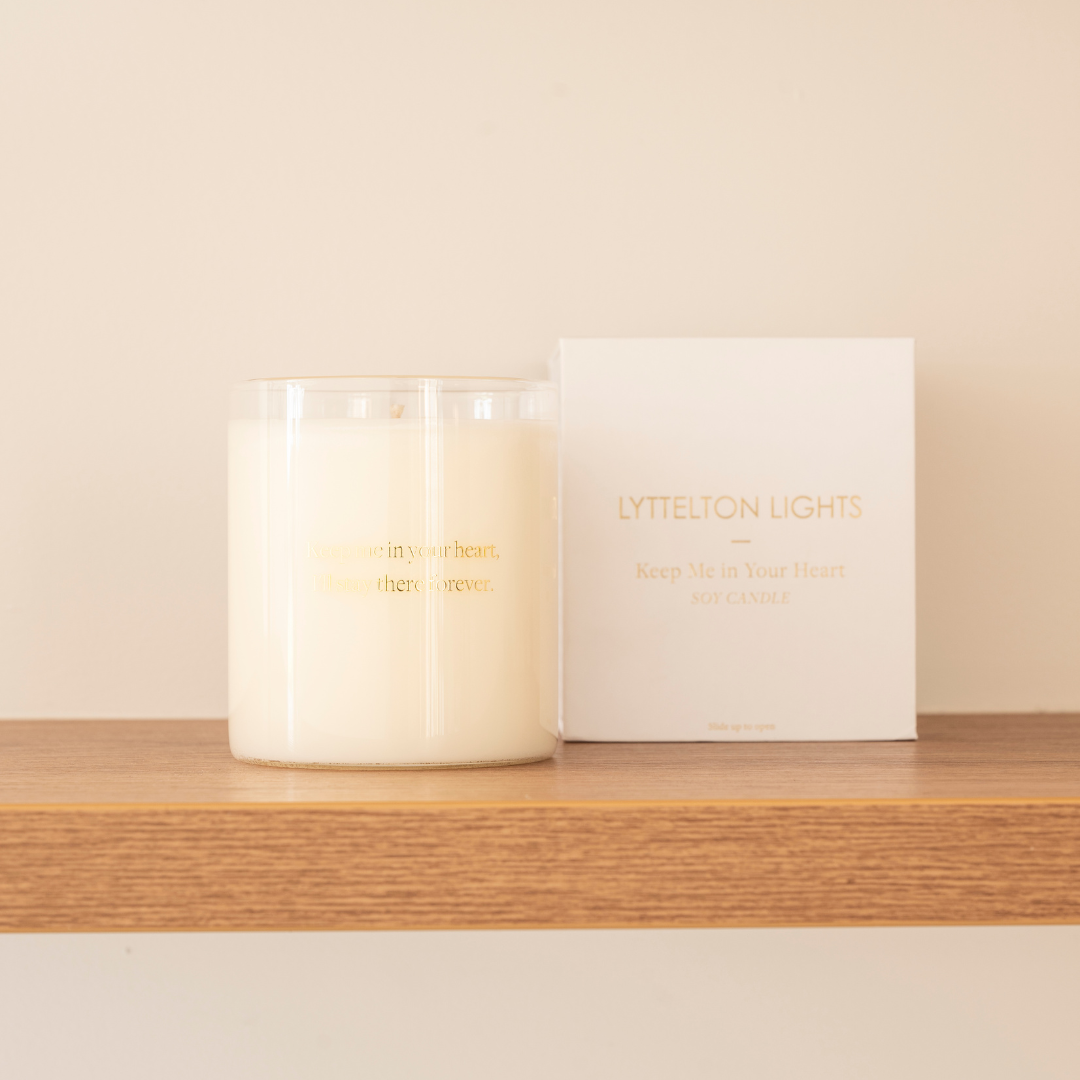 white candle in glass jar on table with box