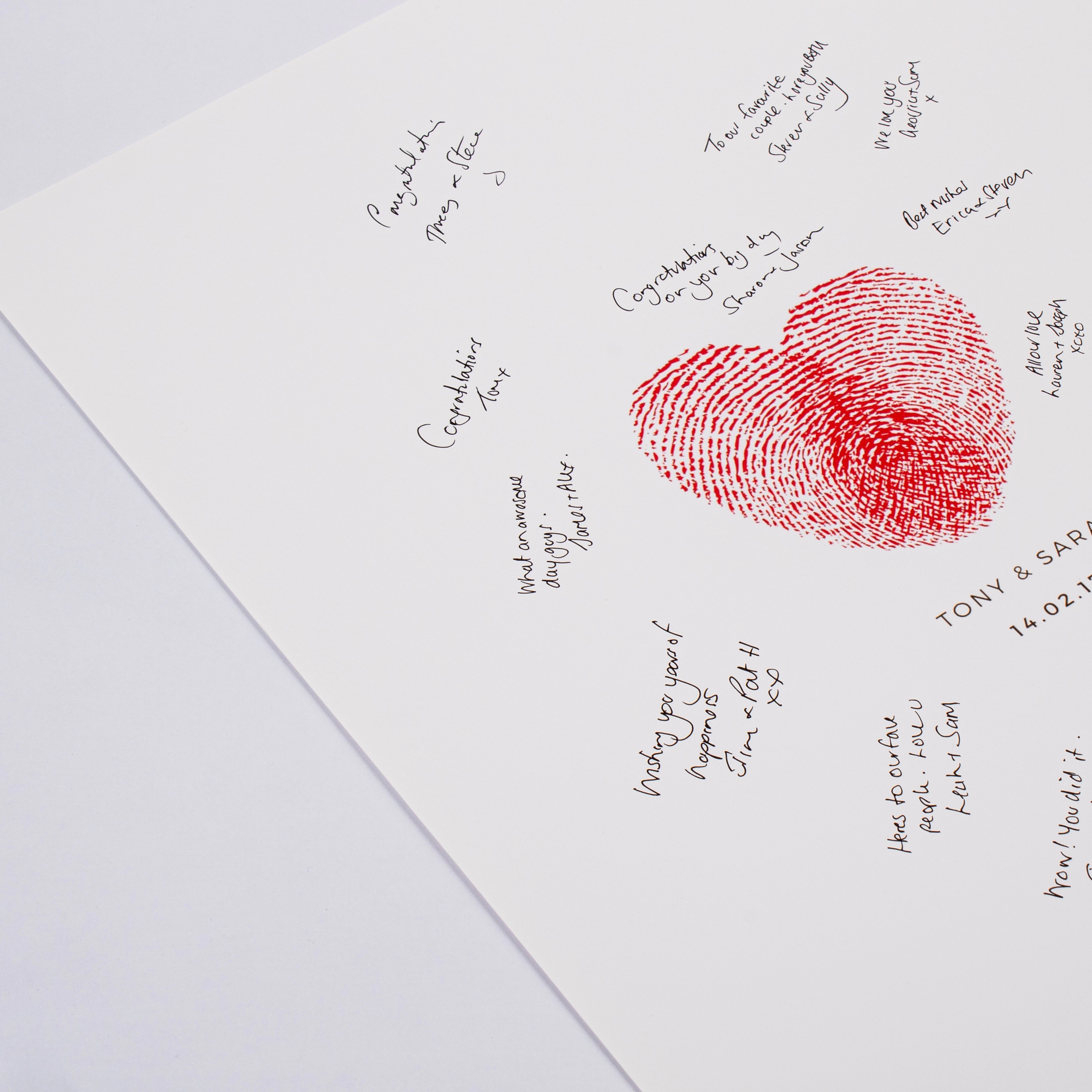 Close-up of a red fingerprint-style heart with guests’ handwritten wedding messages around it