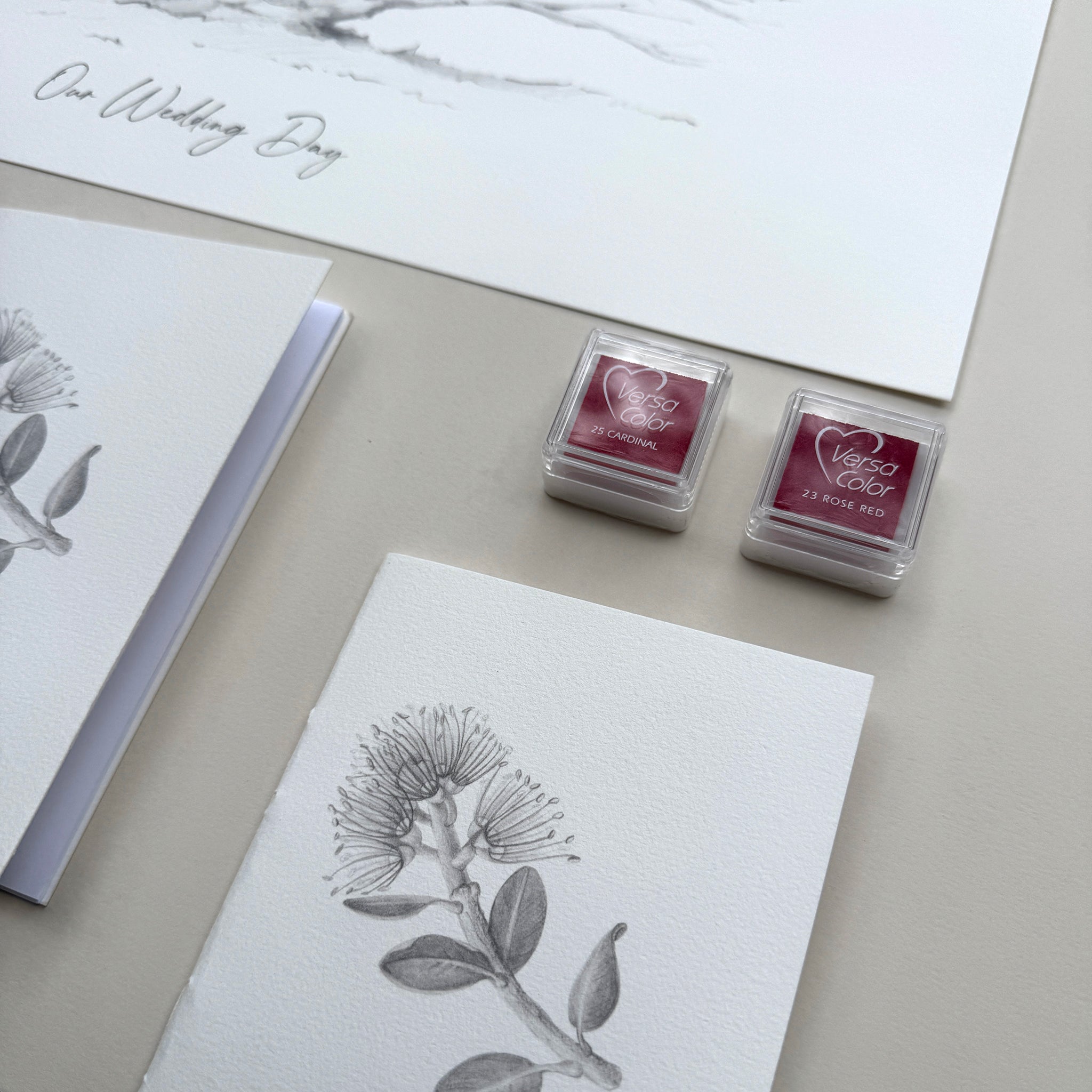 Two ink pads with floral designs on a surface with stationery items.