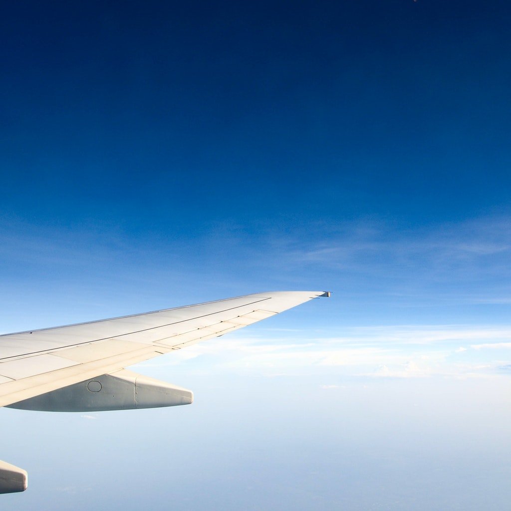 blue sky and clouds with tail of a plane in the foreground
