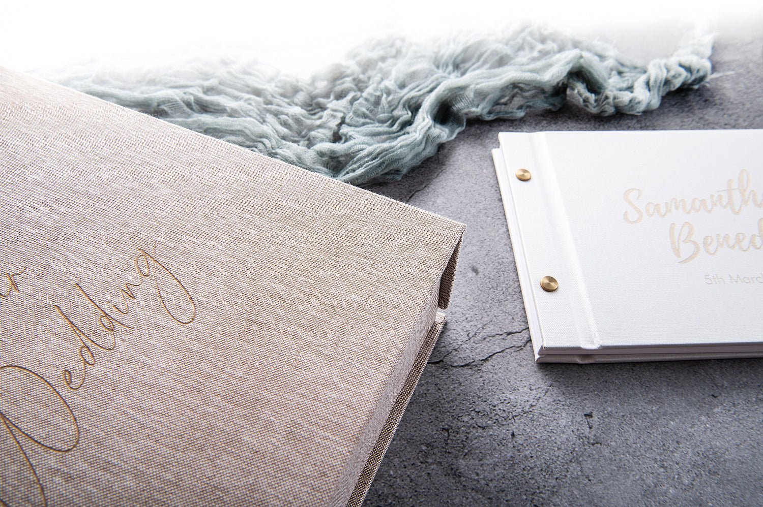 wedding guestbook and keepsake box flat lay on concrete surface with linen fabric