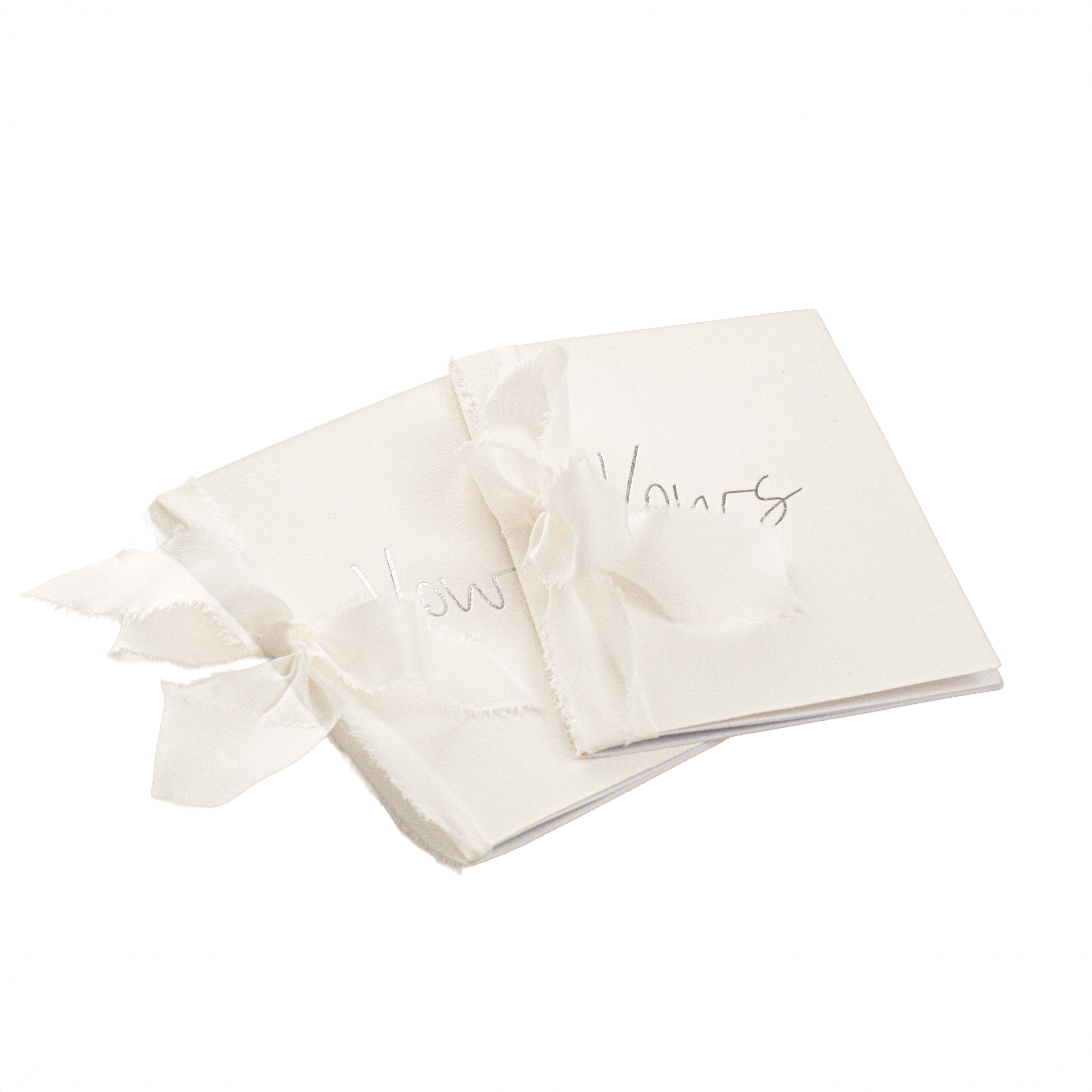 Pair of handcrafted wedding vow books with silk ribbon ties on white artisan paper