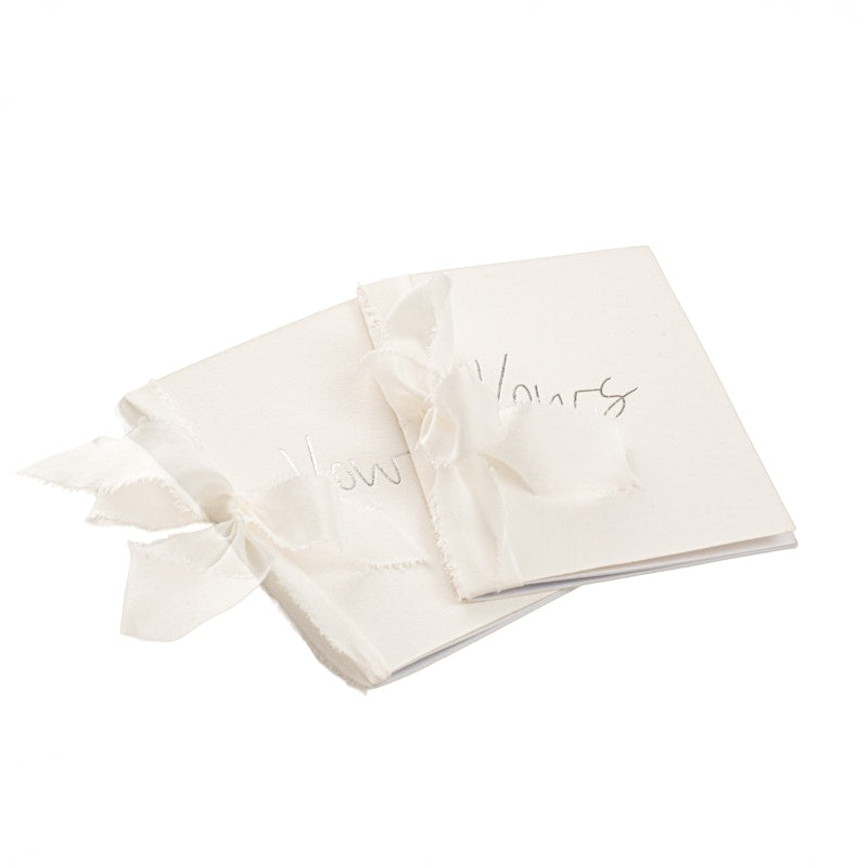 white vow books with silk ribbon and silver foil