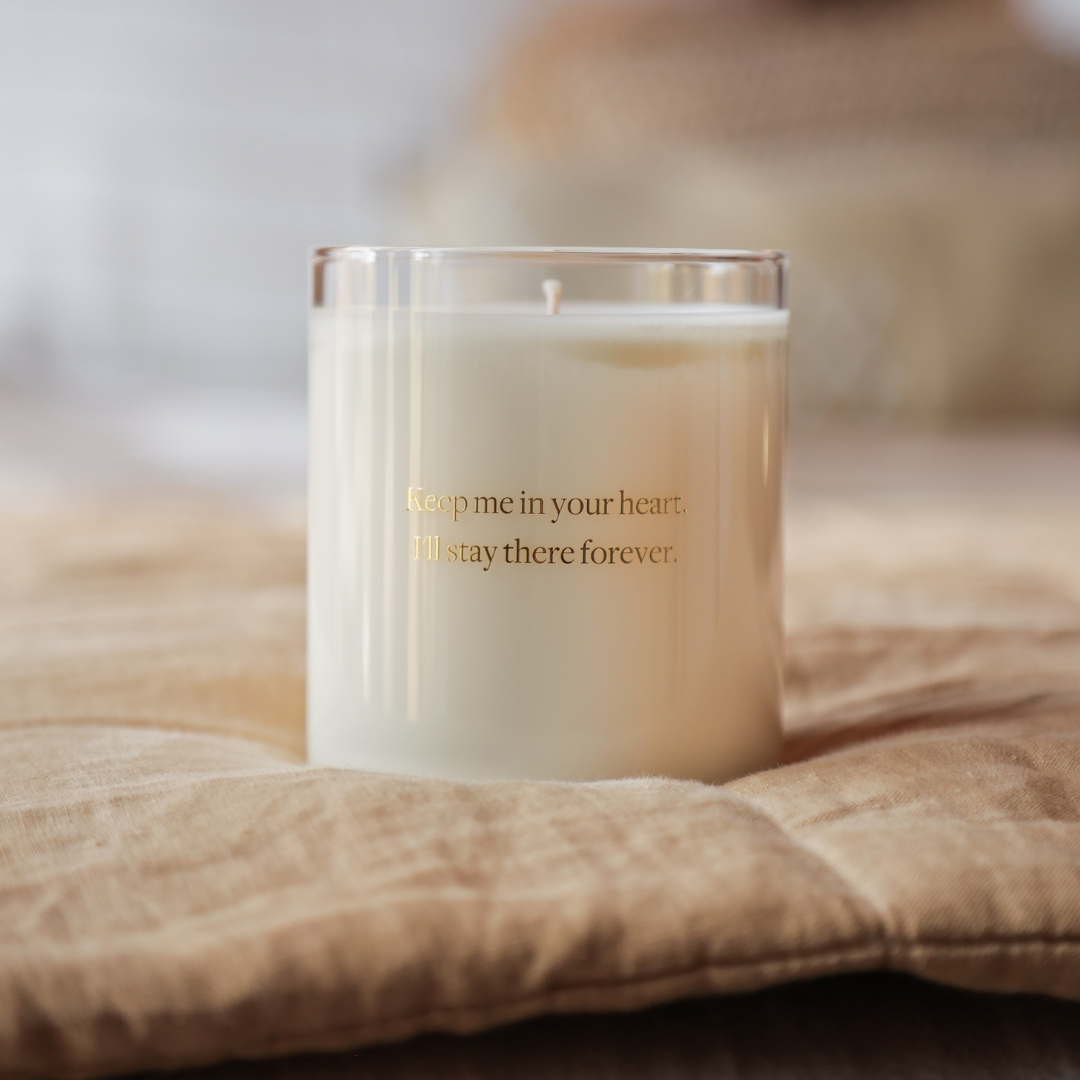 glass candle in jar on beige cushion