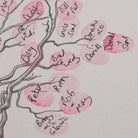 Close-up detail of cherry blossom fingerprint wedding guestbook showing pink fingerprint blossoms and guest names written beside them.