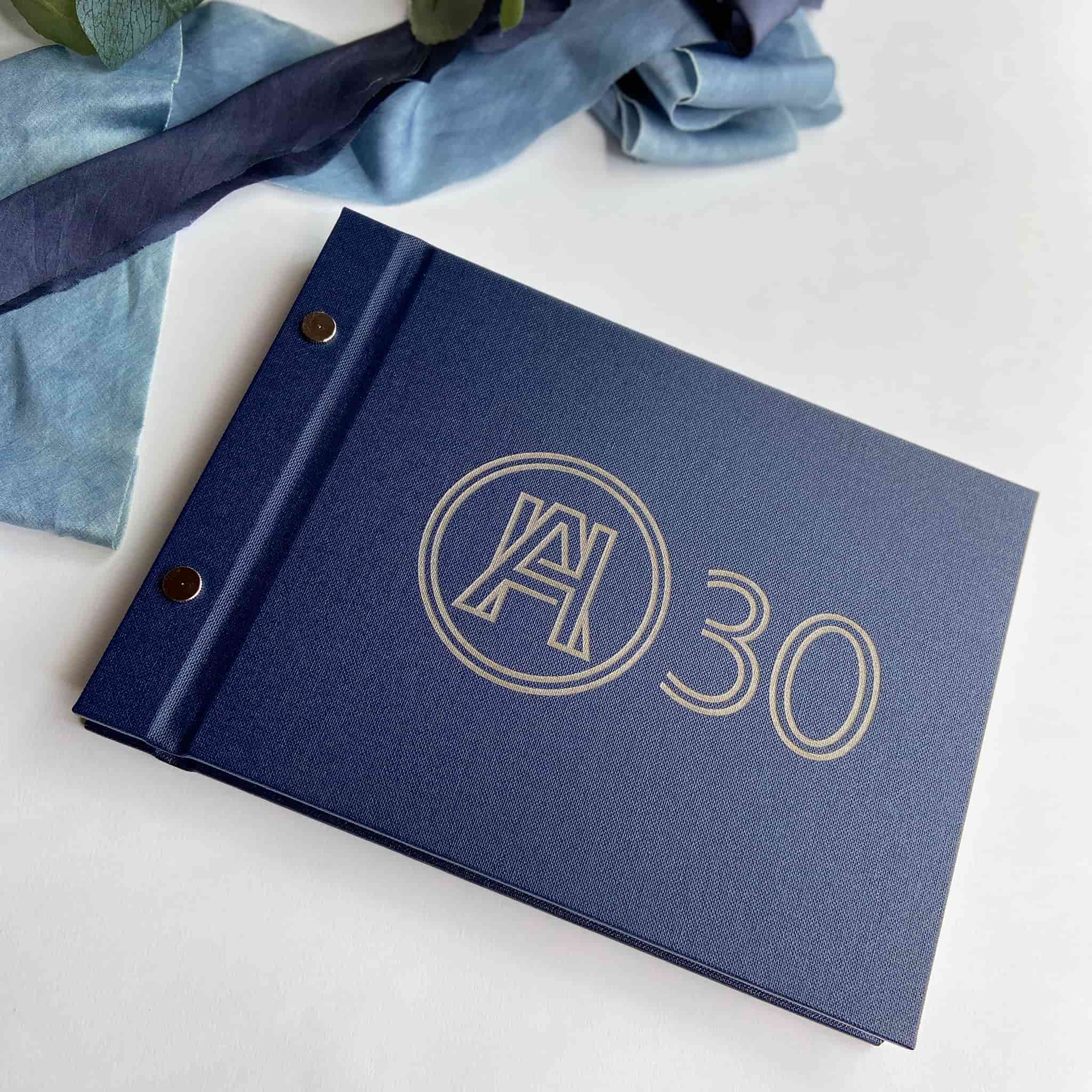 Blue 30th birthday guestbook with gold embossed design on a white surface