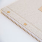 Oatmeal linen guestbook with laser-engraved wood motif insert, angled cover detail