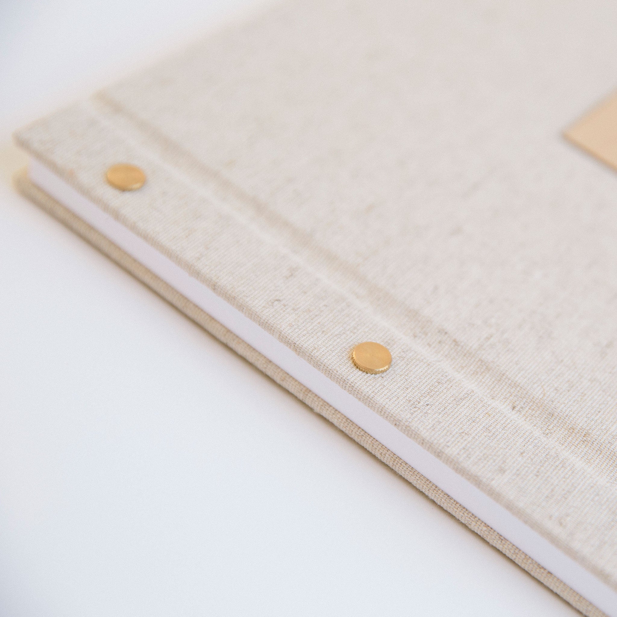 Oatmeal linen guestbook with laser-engraved wood motif insert, angled cover detail