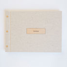 Flat lay of oatmeal linen guestbook ready to ship, wood motif cover detail