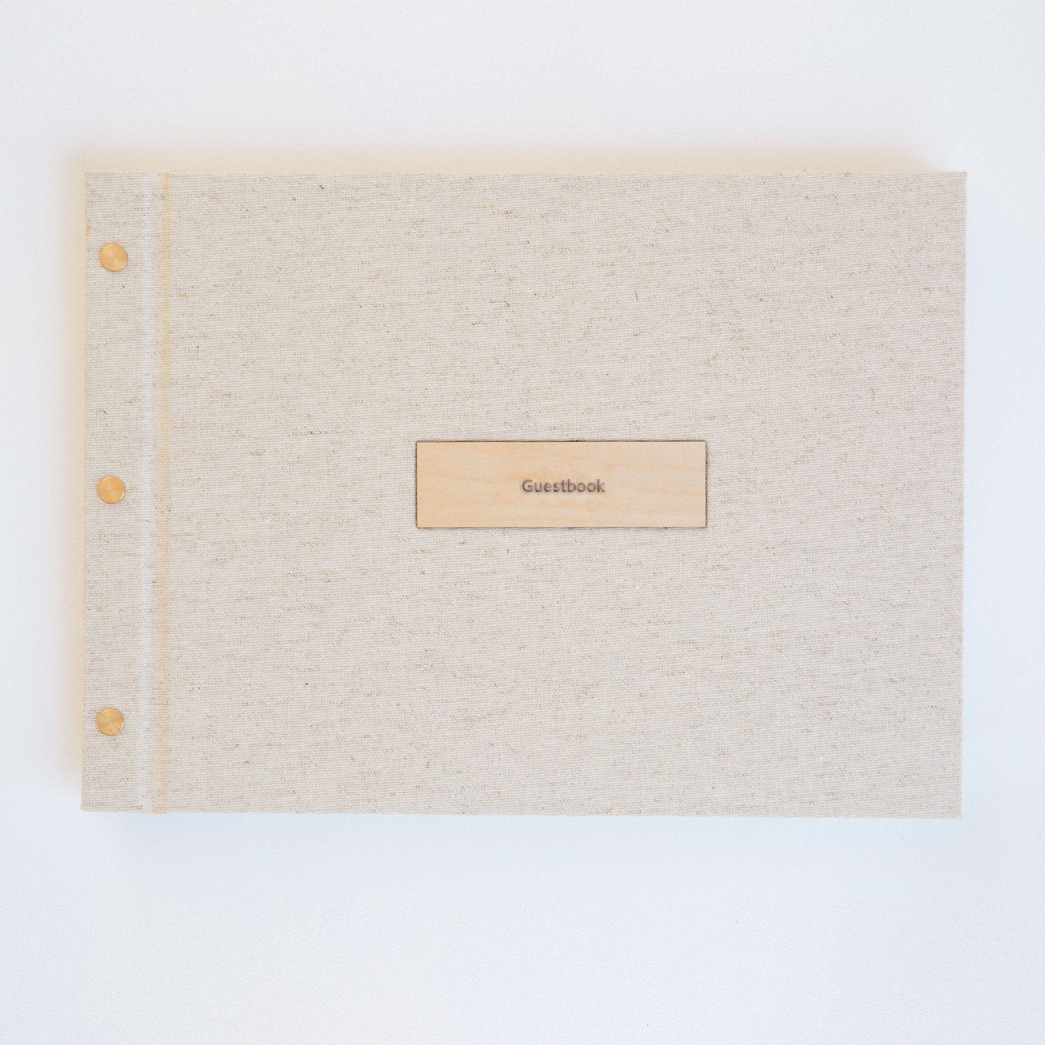 Flat lay of oatmeal linen guestbook ready to ship, wood motif cover detail