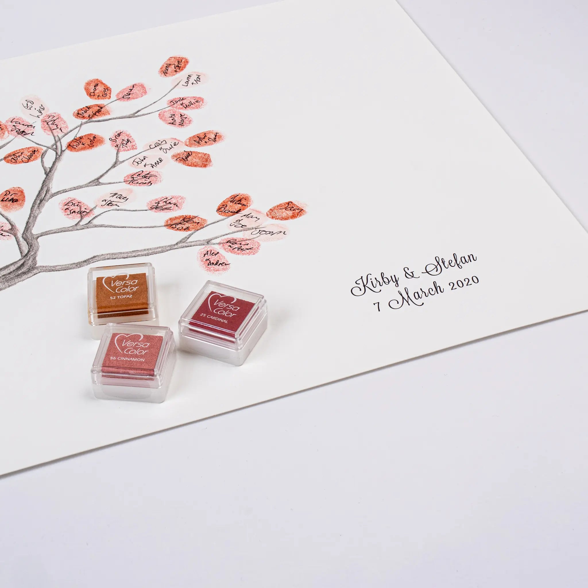 Three small ink pads with red and brown stamping inks placed on a white art print featuring a wanaka tree illustration and the sample text 'Kirby & Stefan 7 March 2020'.